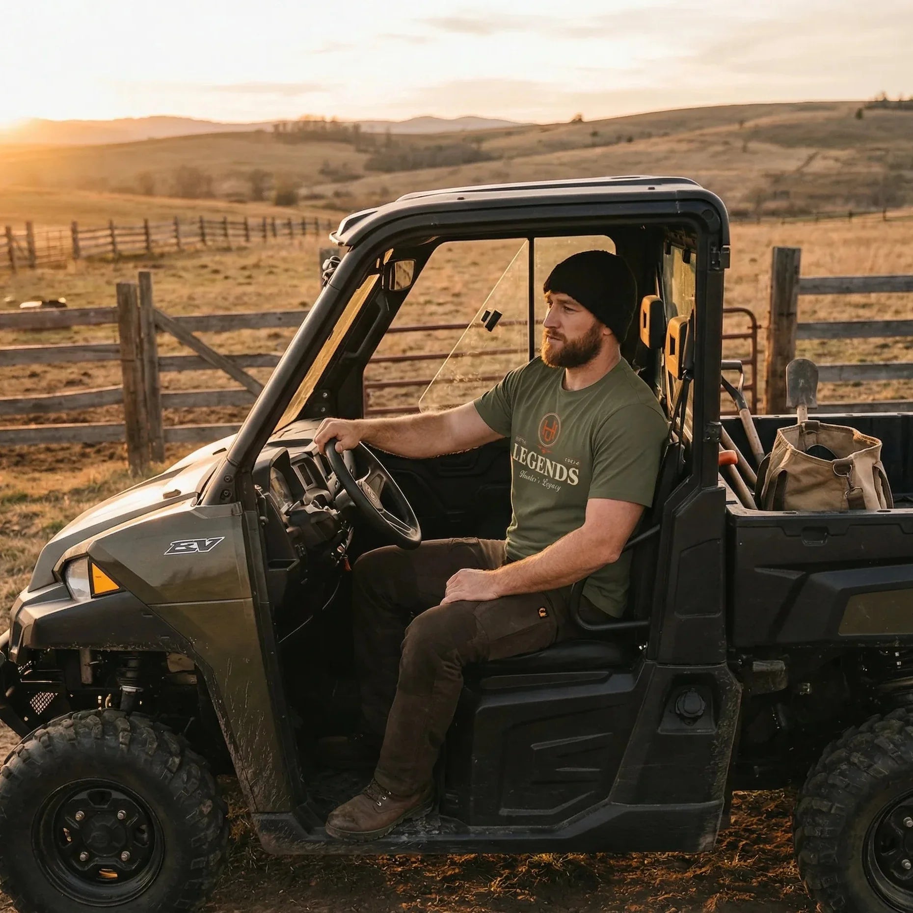 Man sitting in an off-road vehicle on a rural landscape with sunset.